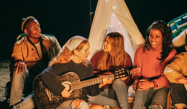 Teens sitting at campfire with guitar