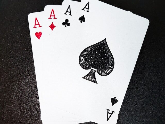 Four cards - the aces of hearts, diamonds, clubs, and spades - laying on a black background like someone set their hand down to show them off.